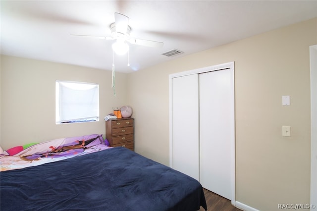 bedroom with a closet, dark wood-type flooring, and ceiling fan