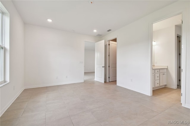 unfurnished bedroom with connected bathroom and light tile patterned floors