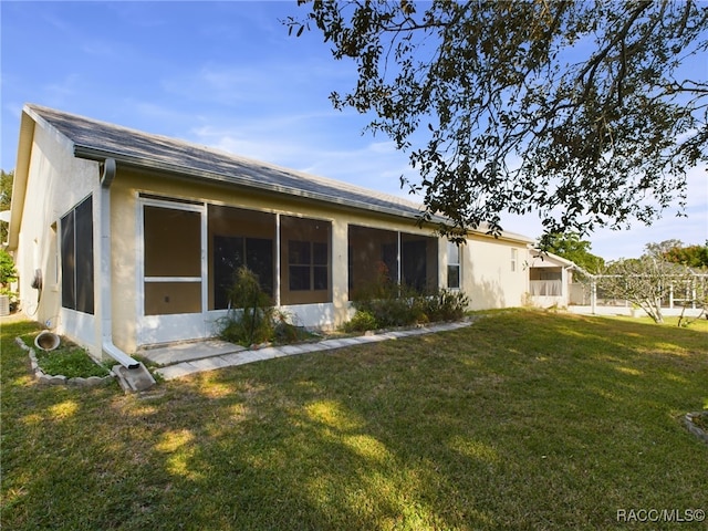 rear view of house with a lawn and a sunroom