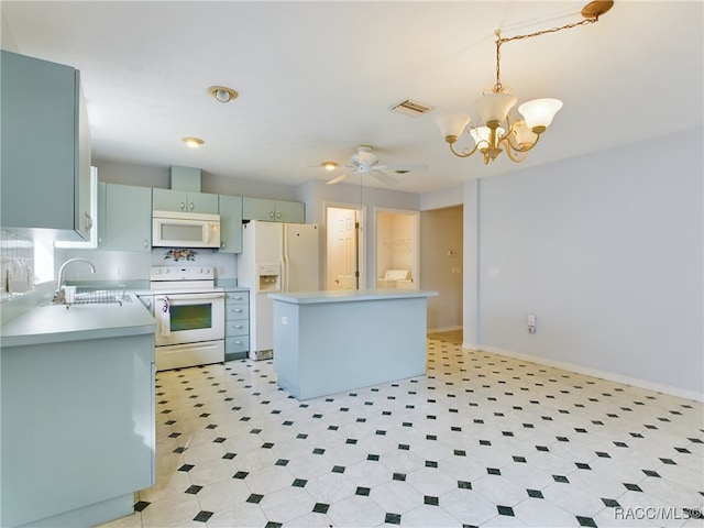 kitchen with white appliances, ceiling fan with notable chandelier, sink, hanging light fixtures, and a kitchen island