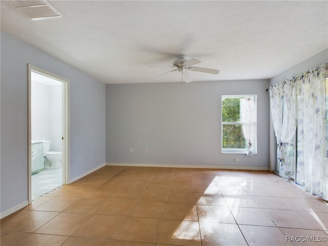 empty room with ceiling fan, light tile patterned flooring, and a textured ceiling