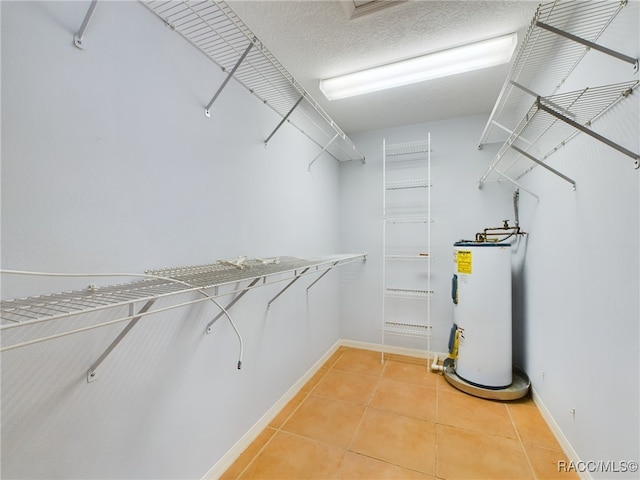 walk in closet featuring tile patterned flooring and water heater