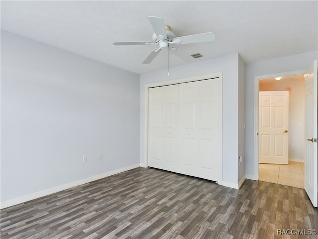 unfurnished bedroom with a textured ceiling, dark hardwood / wood-style flooring, a closet, and ceiling fan