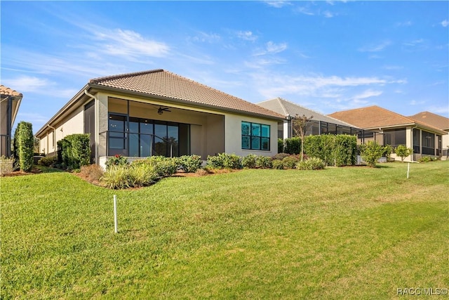 rear view of house with ceiling fan and a lawn