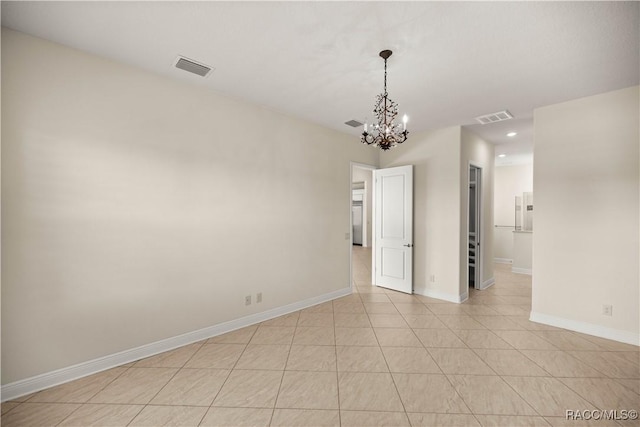 spare room featuring an inviting chandelier and light tile patterned flooring