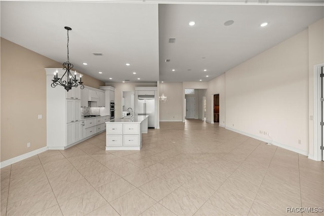 kitchen with white cabinetry, hanging light fixtures, an island with sink, a notable chandelier, and stainless steel appliances