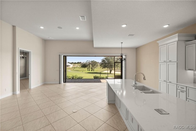 kitchen featuring light stone countertops, sink, pendant lighting, and light tile patterned floors