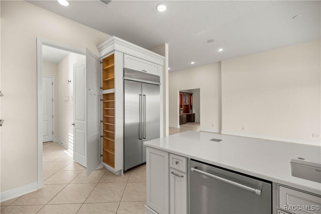 kitchen featuring sink, light tile patterned flooring, white cabinets, and appliances with stainless steel finishes