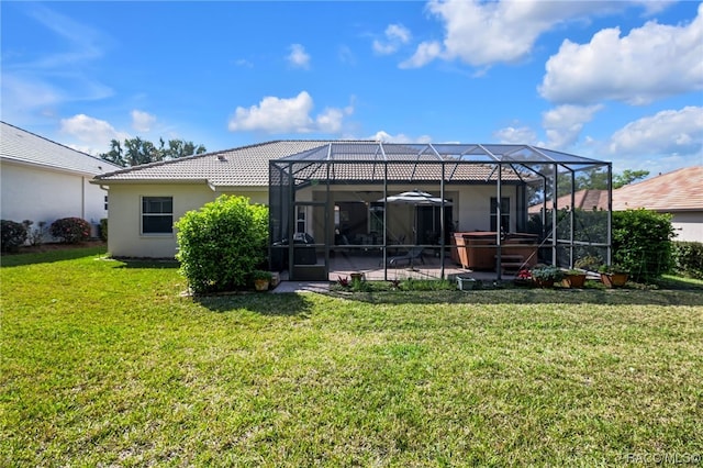 back of house featuring glass enclosure, a patio area, a yard, and a hot tub