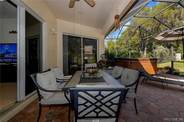 view of patio / terrace featuring ceiling fan, glass enclosure, and a hot tub