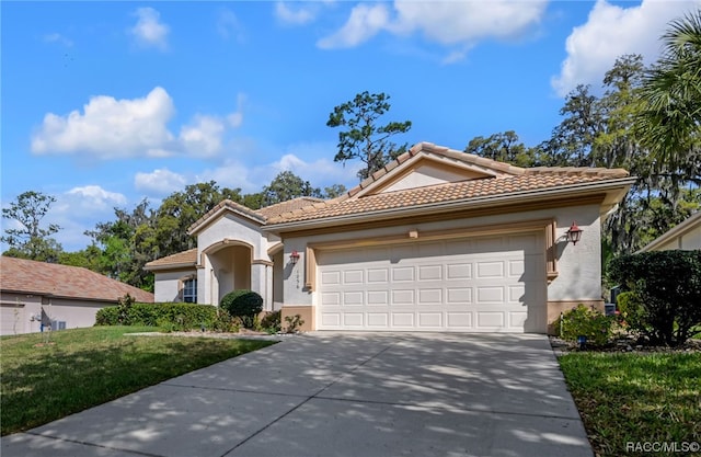 mediterranean / spanish-style house with a garage and a front lawn