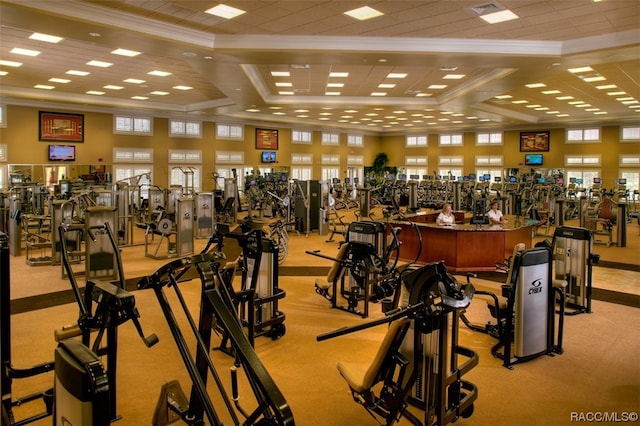 exercise room featuring light colored carpet, ornamental molding, and coffered ceiling