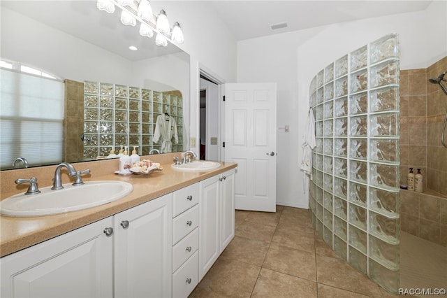 bathroom with a tile shower, tile patterned flooring, and vanity