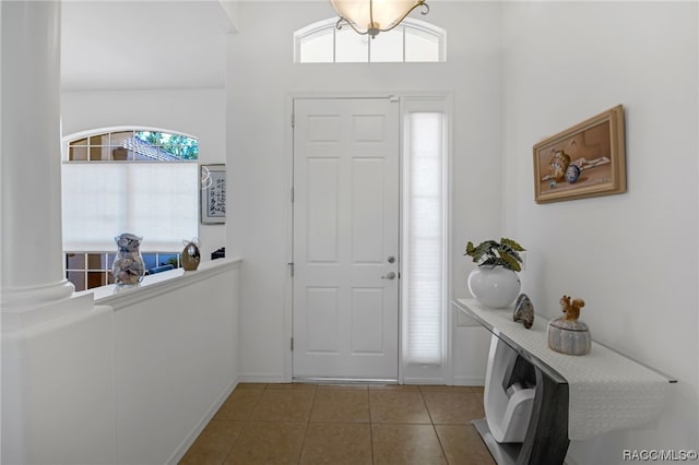 entrance foyer featuring decorative columns, tile patterned floors, and plenty of natural light