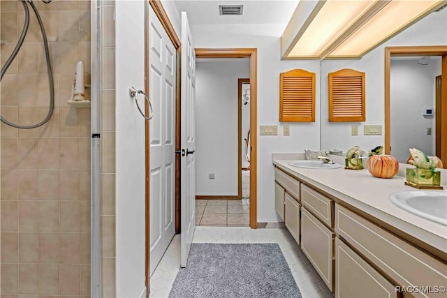 bathroom with tiled shower, vanity, and tile patterned flooring