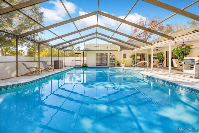 view of swimming pool featuring area for grilling, a patio area, ceiling fan, and glass enclosure