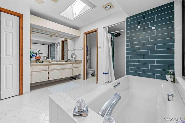 full bathroom featuring tile patterned floors, toilet, shower with separate bathtub, a skylight, and vanity