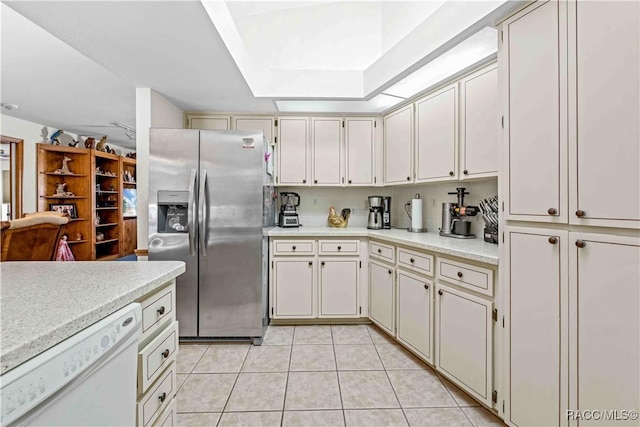 kitchen with light tile patterned flooring, a raised ceiling, dishwasher, and stainless steel refrigerator with ice dispenser