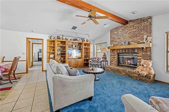 tiled living room featuring a brick fireplace, lofted ceiling with beams, rail lighting, and ceiling fan