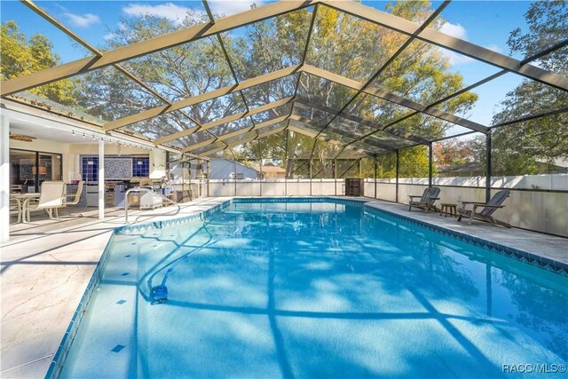 view of pool featuring glass enclosure and a patio area