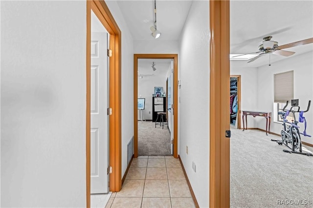 hall with track lighting and light colored carpet