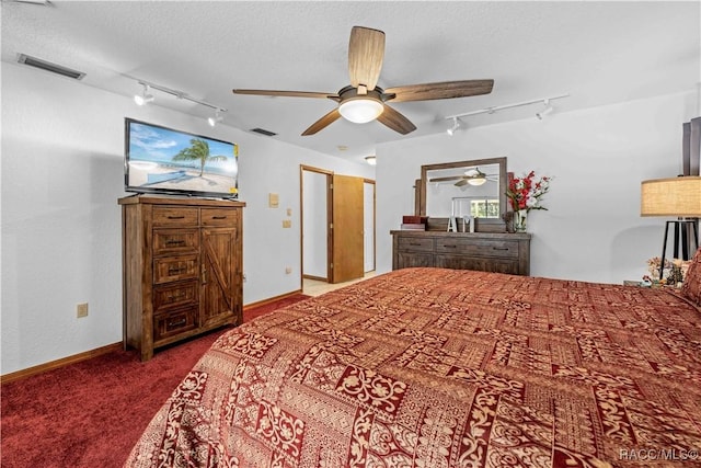 carpeted bedroom with ceiling fan, rail lighting, and a textured ceiling