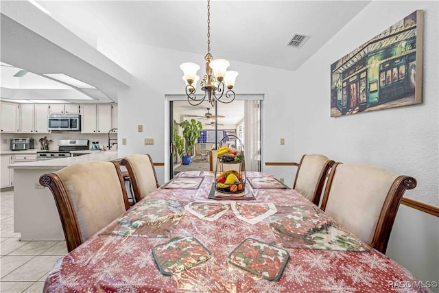 dining room with a notable chandelier, vaulted ceiling, and light tile patterned floors