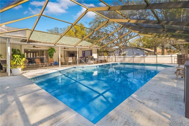 view of swimming pool featuring ceiling fan, a lanai, and a patio