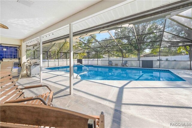 view of swimming pool with area for grilling, glass enclosure, and a patio area