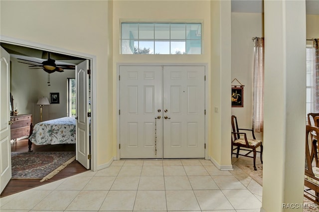 foyer entrance featuring ceiling fan, a towering ceiling, and light hardwood / wood-style flooring