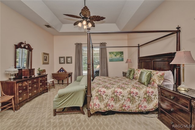 carpeted bedroom featuring ceiling fan and a raised ceiling