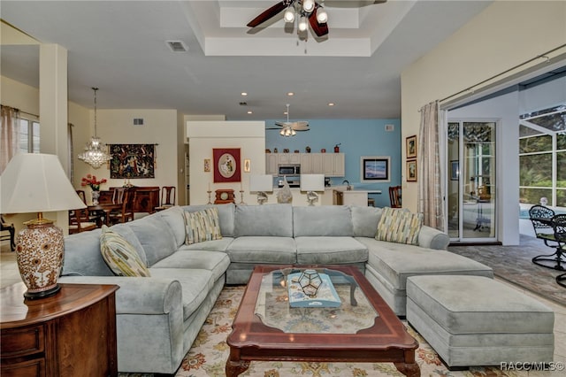 living room with a raised ceiling and ceiling fan