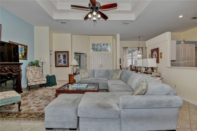 living room featuring light tile patterned floors, a raised ceiling, and ceiling fan