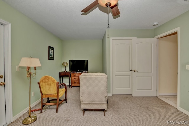 living area featuring light carpet, a textured ceiling, and ceiling fan