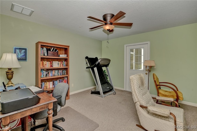 carpeted office space featuring ceiling fan and a textured ceiling