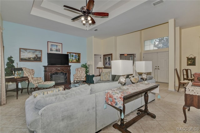 tiled living room featuring a raised ceiling, ceiling fan, and a towering ceiling