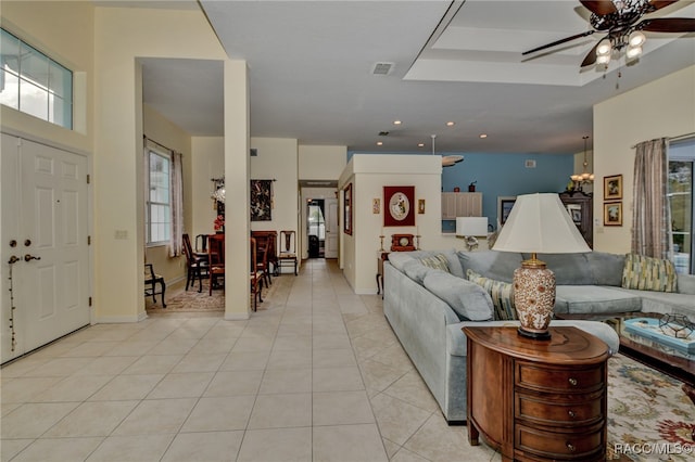 tiled living room with ceiling fan with notable chandelier