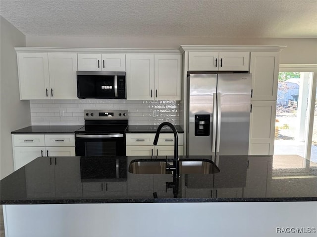 kitchen featuring a sink, backsplash, white cabinetry, dark stone counters, and appliances with stainless steel finishes