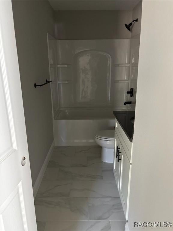 bathroom with toilet, marble finish floor,  shower combination, baseboards, and vanity