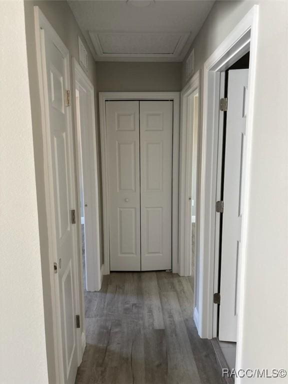 corridor with attic access and wood finished floors