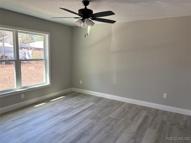 empty room featuring wood finished floors, baseboards, and ceiling fan