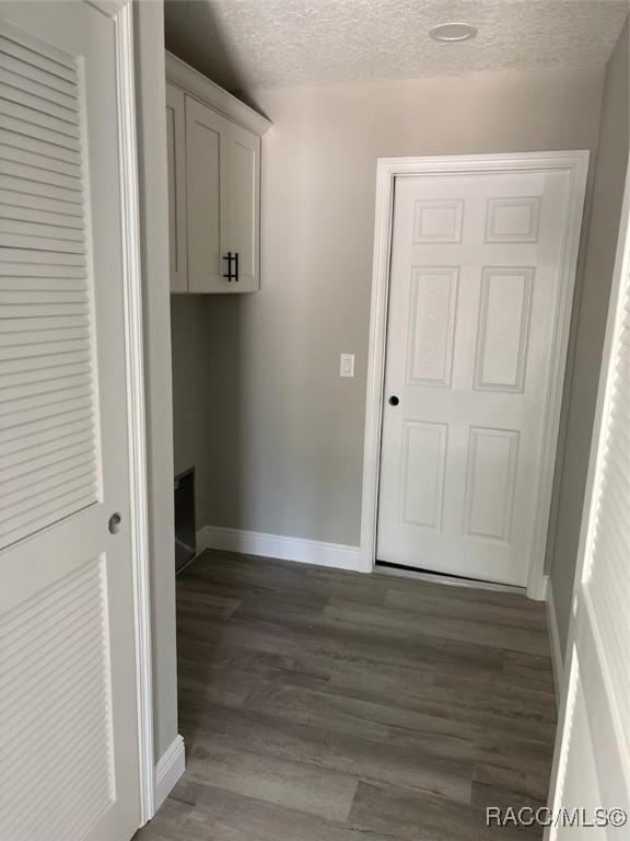 clothes washing area featuring dark wood-style floors, baseboards, and a textured ceiling