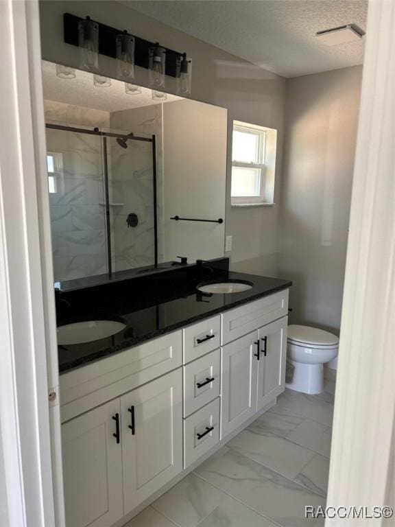 full bathroom featuring toilet, marble finish floor, a stall shower, a sink, and a textured ceiling