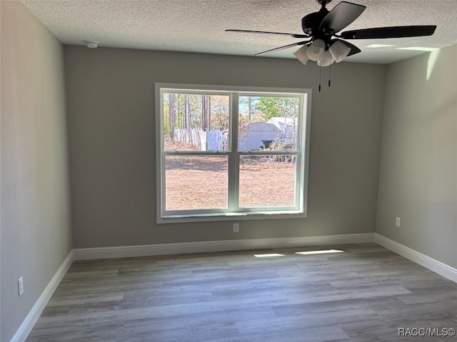 unfurnished room with a textured ceiling, baseboards, a ceiling fan, and wood finished floors