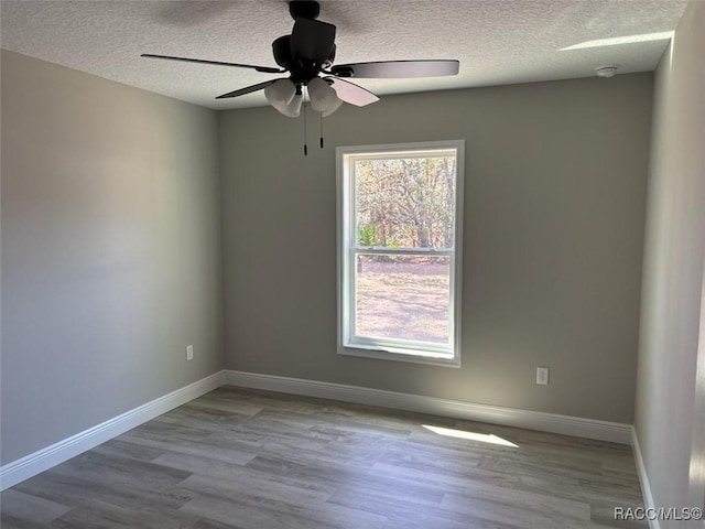 spare room featuring a textured ceiling, a ceiling fan, baseboards, and wood finished floors