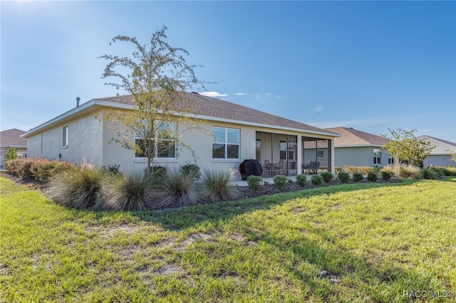 rear view of property with a yard and a sunroom