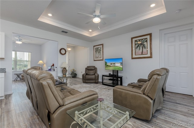 living room with a tray ceiling, light hardwood / wood-style flooring, and ceiling fan