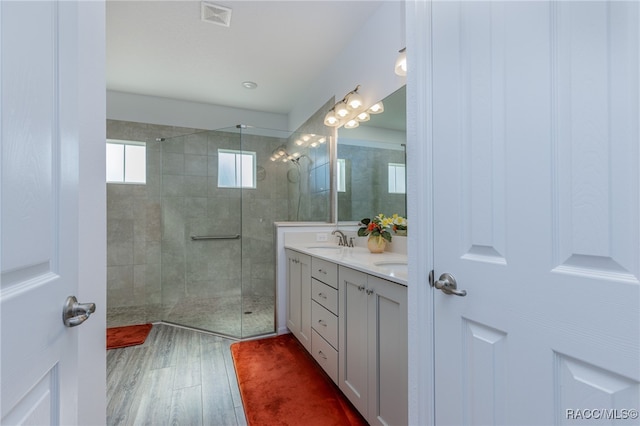 bathroom featuring hardwood / wood-style floors, vanity, and a tile shower