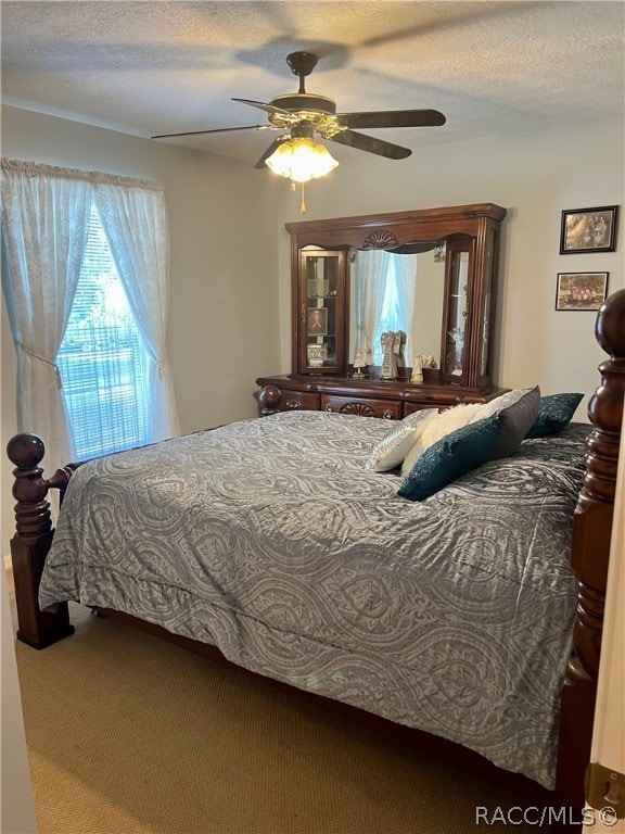 bedroom with ceiling fan, carpet floors, and a textured ceiling