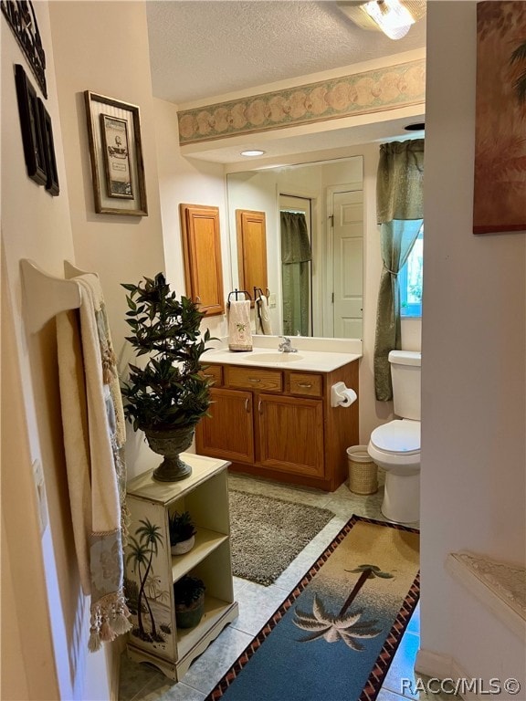 bathroom featuring vanity, a textured ceiling, toilet, and tile patterned flooring